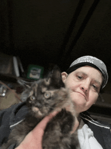 a woman holds a cat in her arms with a harley davidson sign in the background