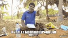 a man in a blue shirt is sitting in the dirt with a bottle of water in front of him