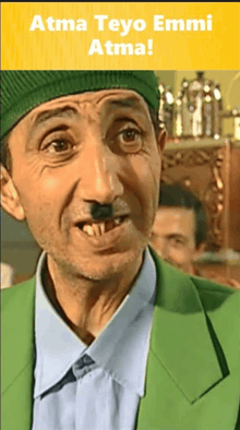 a man wearing a green hat and a green jacket with the words atma teyo emmi atma on the bottom
