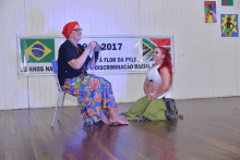 two women are kneeling in front of a sign that says 2017 on it