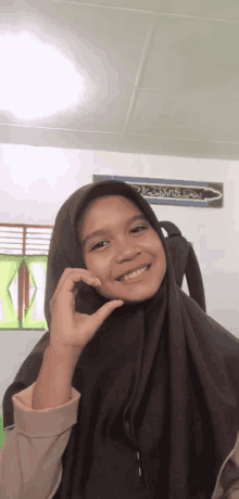 a girl wearing a hijab making a heart with her hand