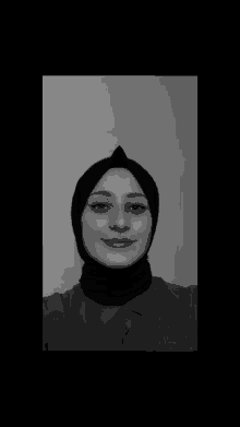 a black and white photo of a woman wearing a hijab and smiling