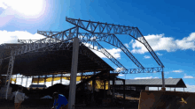 a large metal structure with a blue sky and clouds behind it