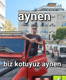 a young man leaning on the door of a red car with aynen biz kotuyuz aynen written on the bottom