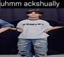 a person wearing ripped jeans and a white shirt that says uhmm ackshually on it