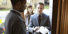 a man in a suit is holding a bible and talking to a woman