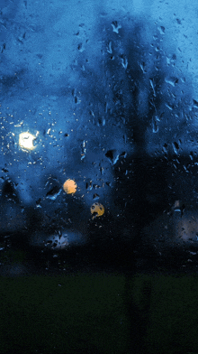 a window with a lot of rain drops on it and a light in the background