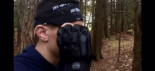 a man wearing a bandana with the word jay on it covering his face in the woods .