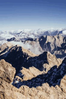 a mountain range with a blue sky and clouds surrounding it