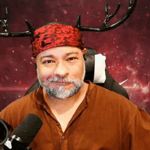 a man with a beard wearing a red headband with antlers on it