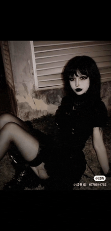 a woman in a black dress and black stockings is sitting on the ground in front of a wall .