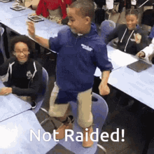 a boy is standing on a chair in a classroom with the words not raided written on the bottom .