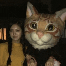 a woman is standing next to a large stuffed cat .