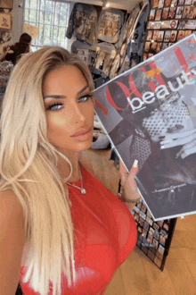 a woman in a red dress is holding a copy of vogue beauty