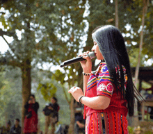 a woman singing into a microphone while wearing a multicolored dress