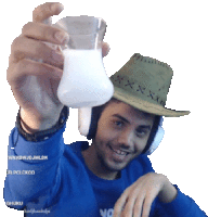 a man wearing a cowboy hat holds a glass of milk