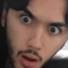 a close up of a man 's face with a beard and a surprised look on his face .