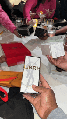 a man holds a bottle of libre perfume in his hand