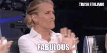 a woman in a white shirt is clapping her hands and saying `` fabulous '' .