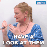 a woman in a blue shirt is holding a pencil and says " have a look at them "