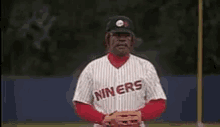 a man in a miners baseball uniform is standing on a baseball field and saying death to the opposition .