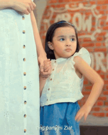 a little girl is holding a woman 's hand in front of a sign that says ang party ni zia