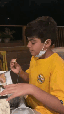 a young boy wearing a yellow shirt with the word surfer on it is eating food