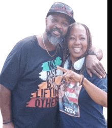 a man and a woman are posing for a picture and the man is wearing a shirt that says " we are by lifting others "