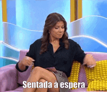 a woman is sitting on a couch with her legs crossed and the words sentada a espera written above her