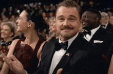 a man in a tuxedo with a mustache is applauding