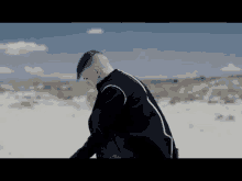 a man in a black jacket and a blue hat is standing in the desert