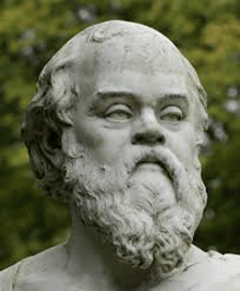 a statue of a man with a beard is standing in front of trees .