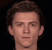 a close up of a young man 's face with a dark background .