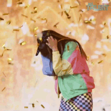 a woman in a colorful jacket is standing in front of a wall with confetti falling from it and the word talent on it