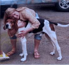 a woman hugging a brown and white dog