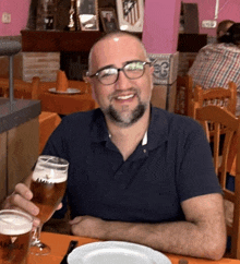 a man sitting at a table holding a glass of beer that says ambar on it