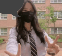 a girl wearing a mask and a tie is giving the peace sign