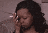 a woman is sitting on a couch smoking a cigarette .