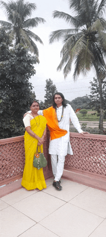 a man and woman pose for a picture on a balcony