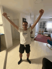 a man wearing a white supreme shirt stands with his arms outstretched