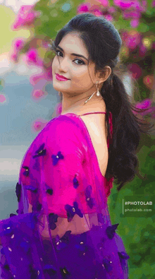 a woman wearing a purple saree with flowers on it