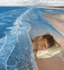 a man is sleeping on a beach with a pillow in the water