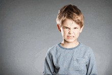 a young boy wearing a striped shirt is making a funny face