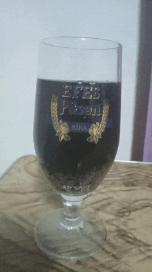 a glass filled with efes pilsen bira sits on a table