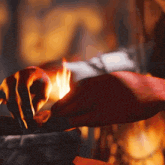 a close up of a person 's hand holding a torch in front of a fire