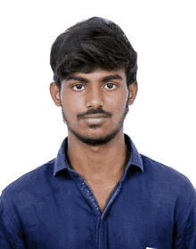 a young man with a beard wearing a blue shirt looks at the camera