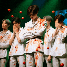 a group of men are covered in blood and tomatoes on their clothes