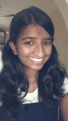 a young girl smiles for the camera with a picture in the background