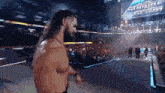 a man with long hair and a beard is standing in front of a sign that says summerslam