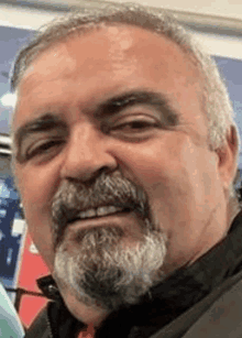 a man with a beard and mustache is smiling for the camera in a close up of his face .